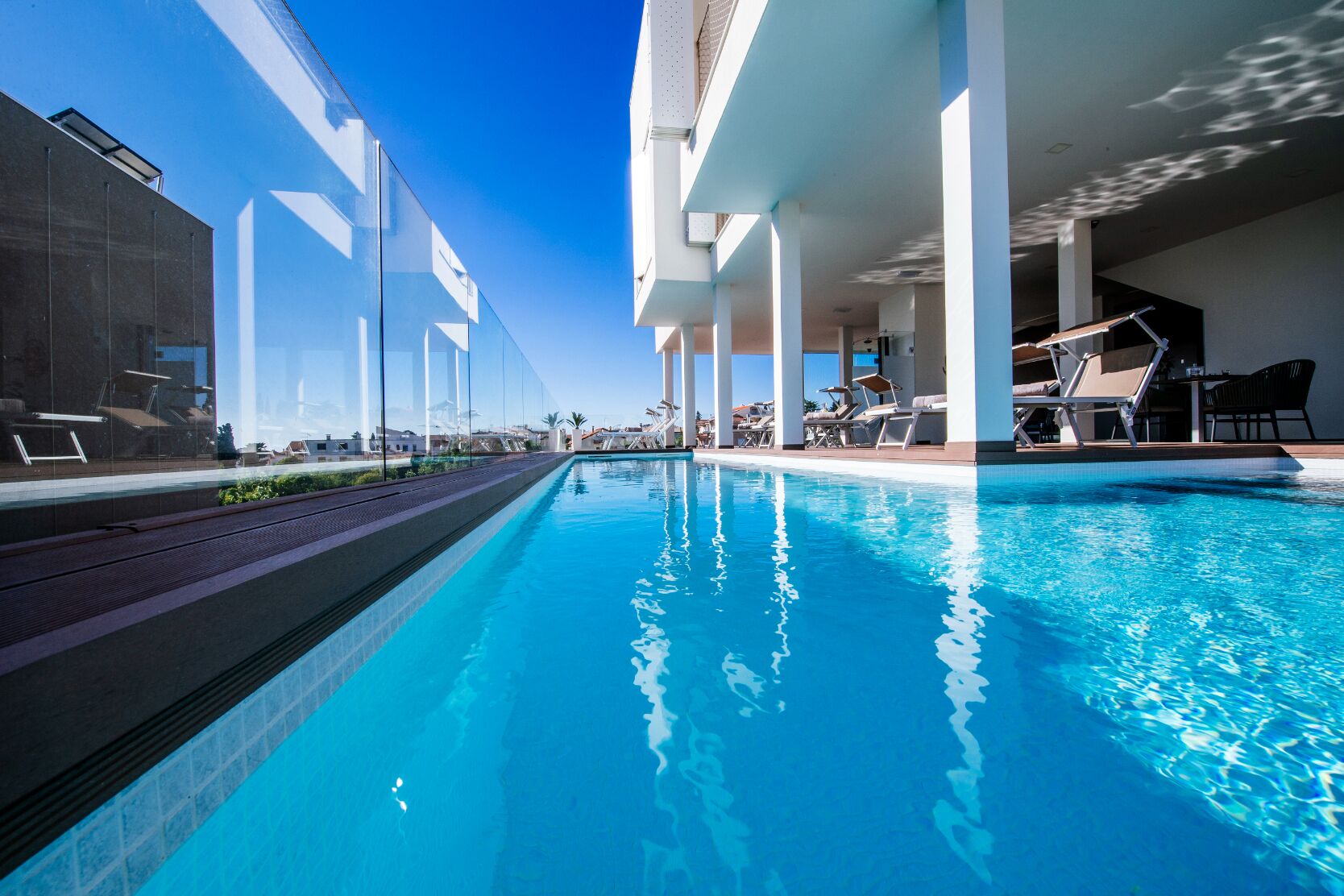 Ein moderner Poolbereich mit klarem, blauem Wasser, Liegestühlen und Blick auf die umliegenden Gebäude.