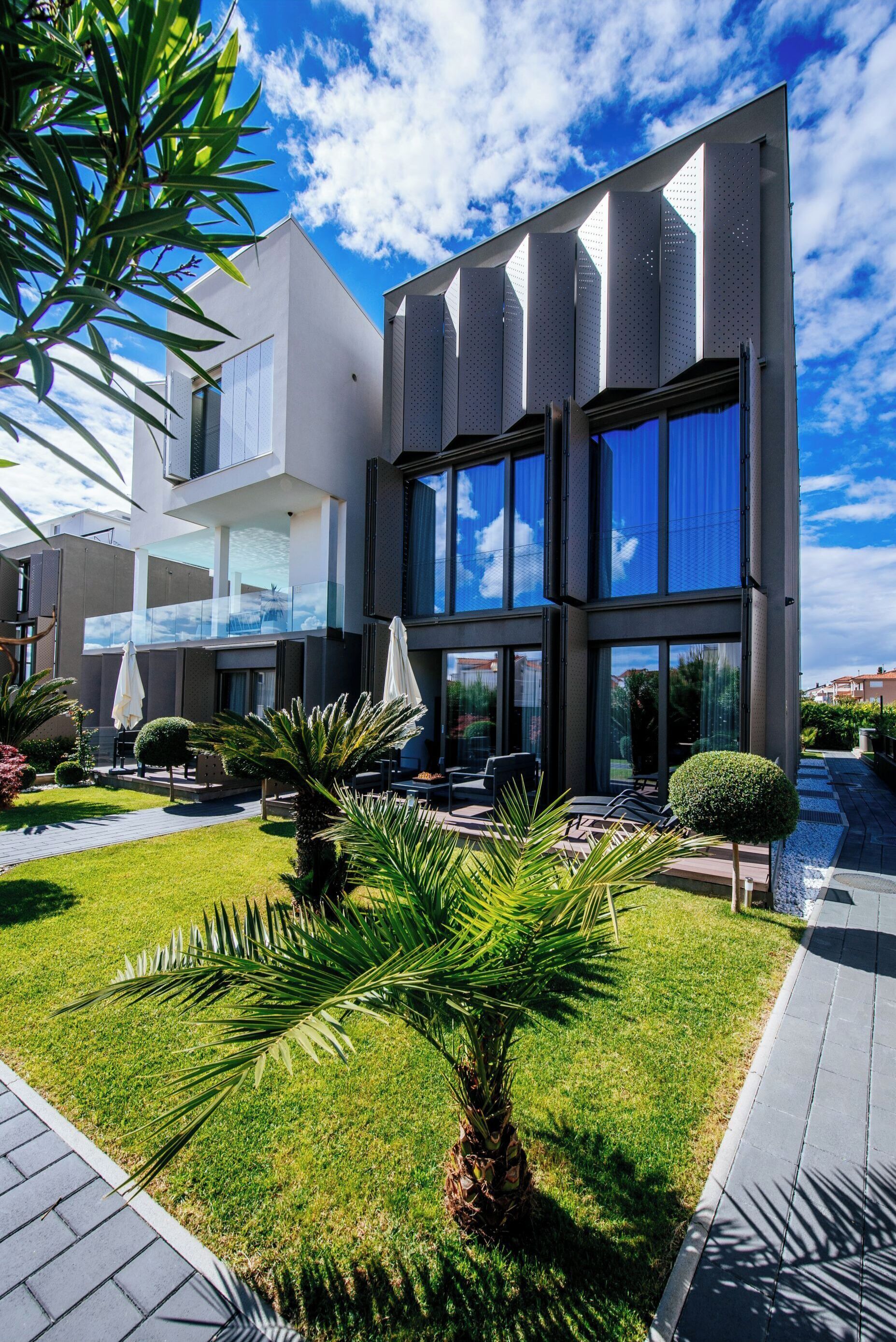 A modern two-story building with a glass facade, outdoor seating area, and well-maintained landscaping.