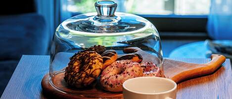 A wooden table with a glass dome-covered dessert, two white cups, and a wooden spoon.