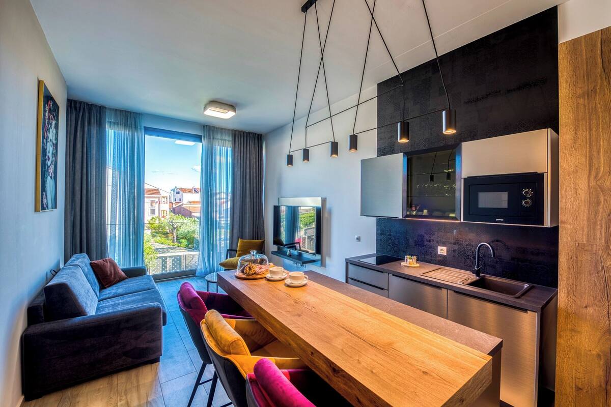 A modern apartment with a dining area, kitchen, and a sofa.