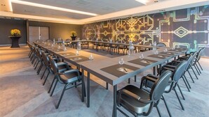 A conference room with a long table, chairs, and a patterned wall. - Van Der Valk Hotel Deventer  (Deventer)