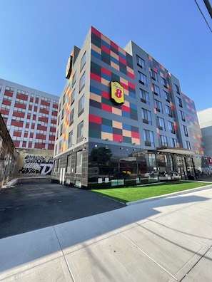 A multi-story hotel with a colorful facade, large windows, and a well-maintained lawn area.