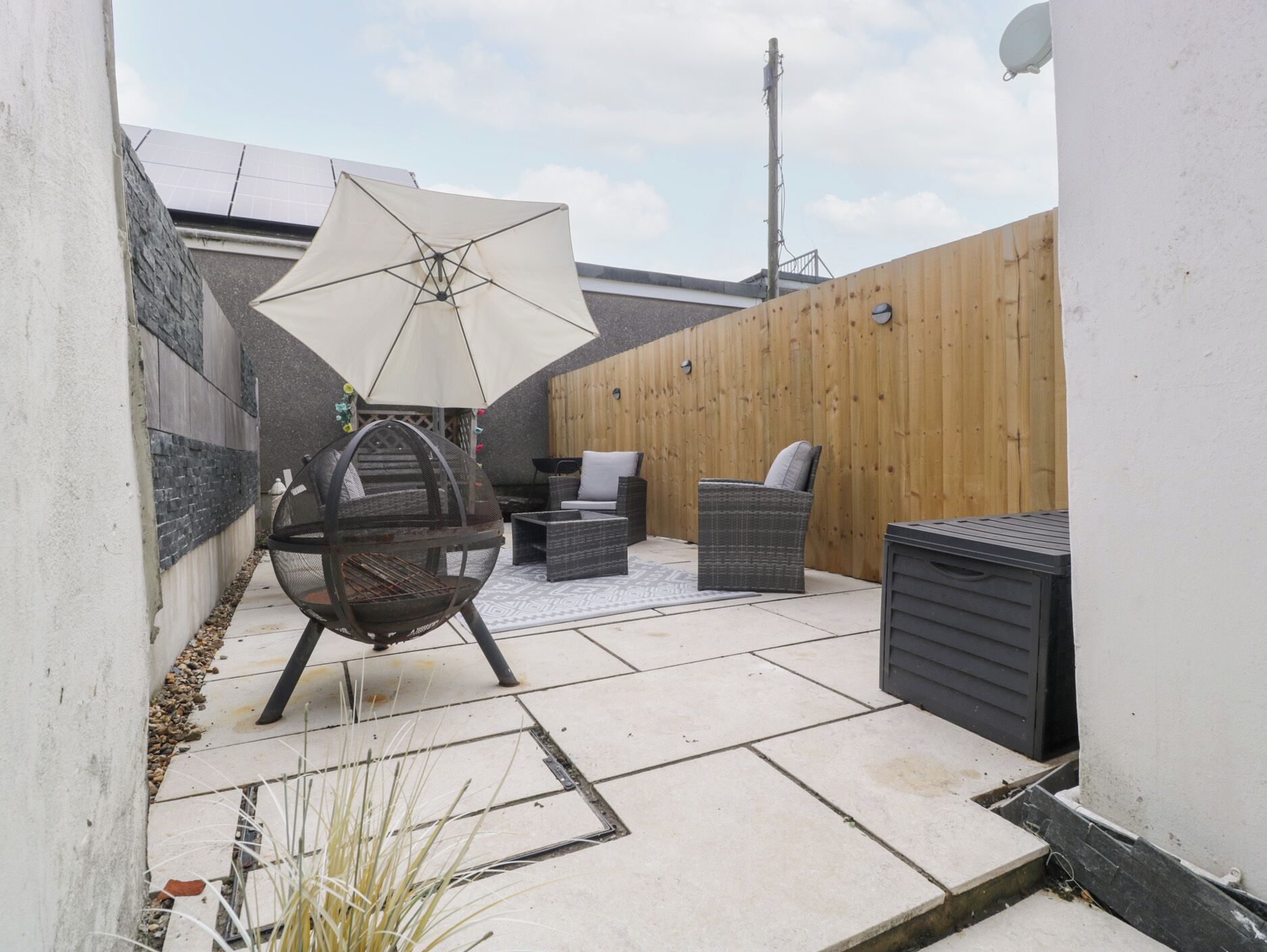 A patio with outdoor furniture, a grill, and a wooden fence.