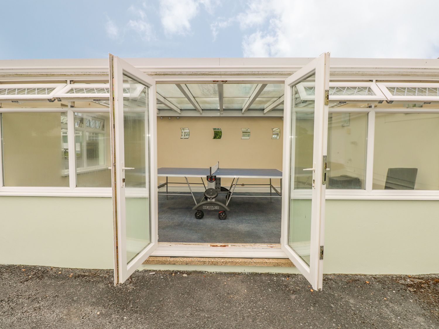 Ein Zimmer mit Tischtennisplatte, Ergometer und einem Fenster mit Blick zum Himmel.