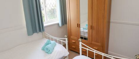 Un dormitorio con dos camas, un armario de madera y una ventana con cortinas.