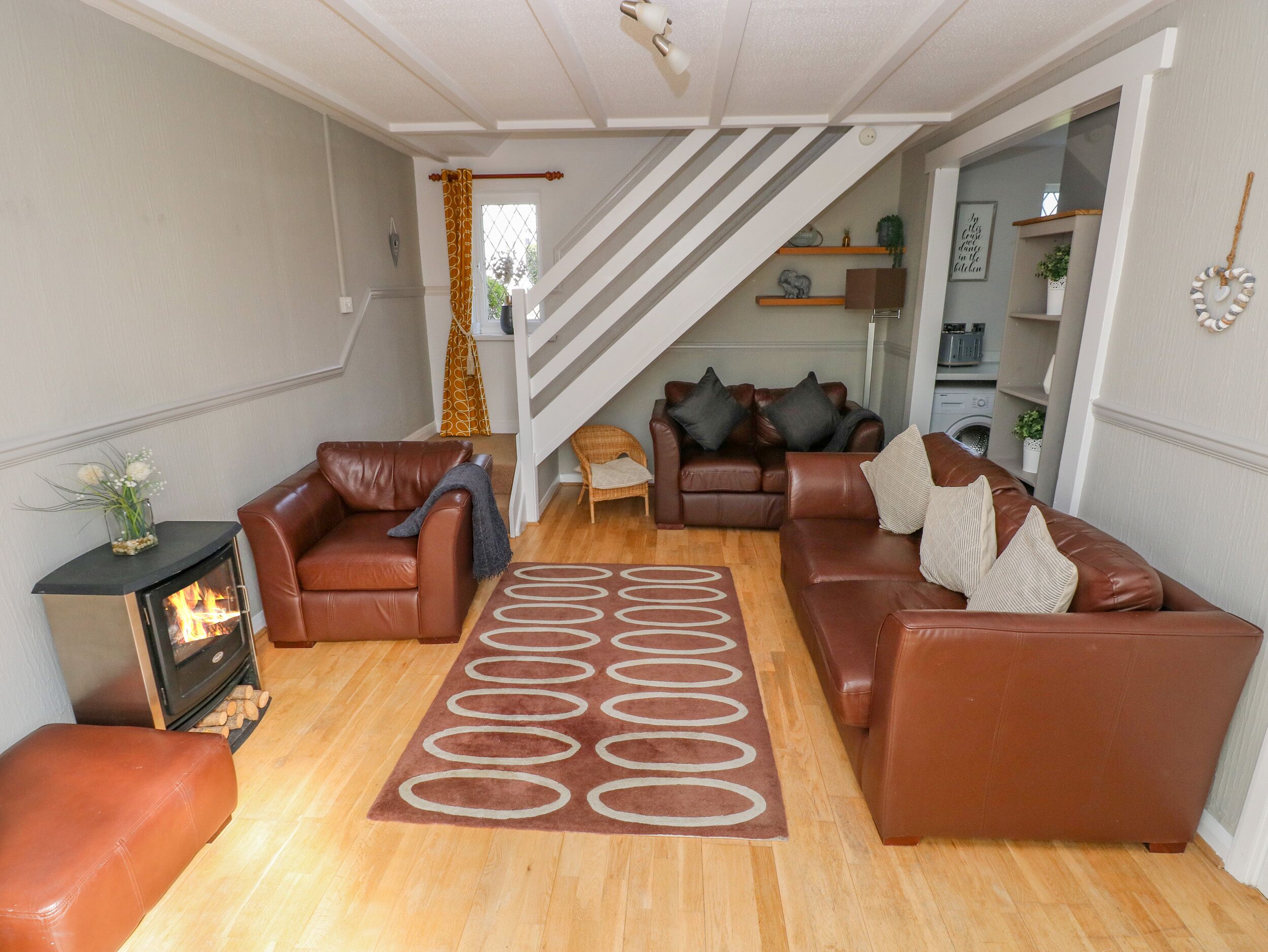 A cozy living room with leather sofas, a fireplace, and a patterned rug.