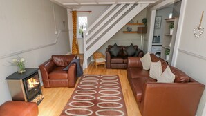 A cozy living room with leather sofas, a fireplace, and a patterned rug. - Grooms Cottage (Tenby)