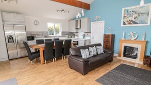 A modern kitchen with a dining area, a fireplace, and a living room with a sofa.
