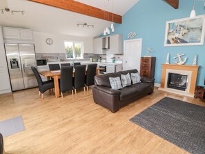 A modern kitchen with a dining area, a fireplace, and a living room with a leather sofa. - Sea View Lodge (Morpeth)