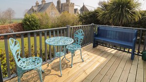 A wooden deck with a blue bench and two turquoise chairs.