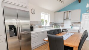 A modern kitchen with stainless steel appliances, a wooden dining table, and black chairs.