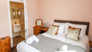 A hotel room with a bed, bedside table, and a bathroom visible through an open door. - Oakhurst (Keswick)