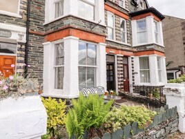 Uma casa geminada tradicional com sacada em arco, fachada de pedra e um pequeno jardim com plantas e uma mesa.