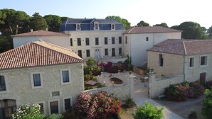 A courtyard with stone buildings, a central fountain, and surrounding greenery. - Luxury Suite with Spa - La Nébuleuse (Vendres)