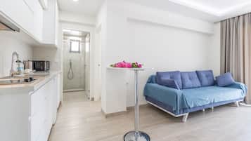A modern apartment with a kitchen, a living area with a sofa, and a small table with flowers.