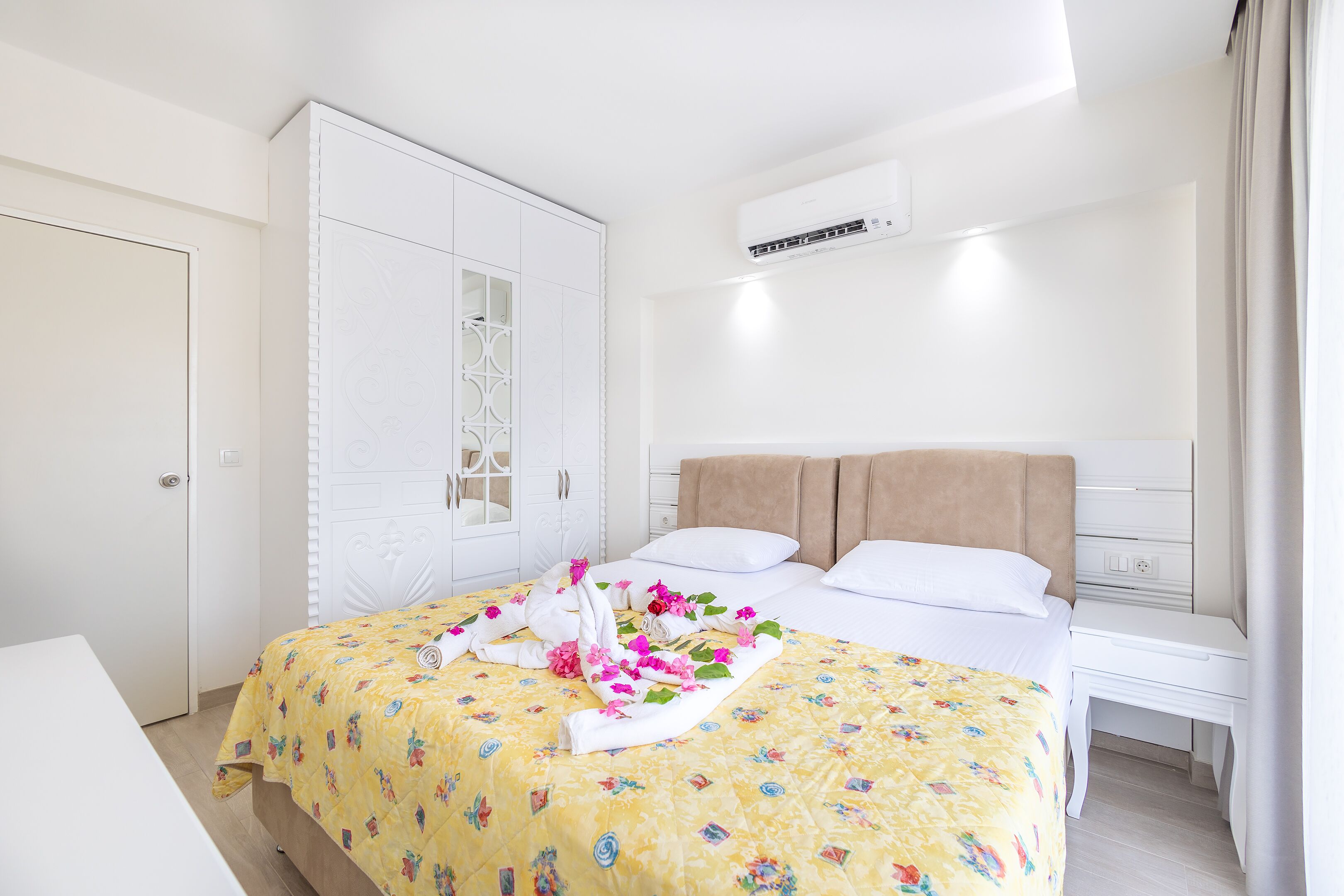 Een hotelkamer met een bed, nachtkastje, kledingkast en een airconditioning.