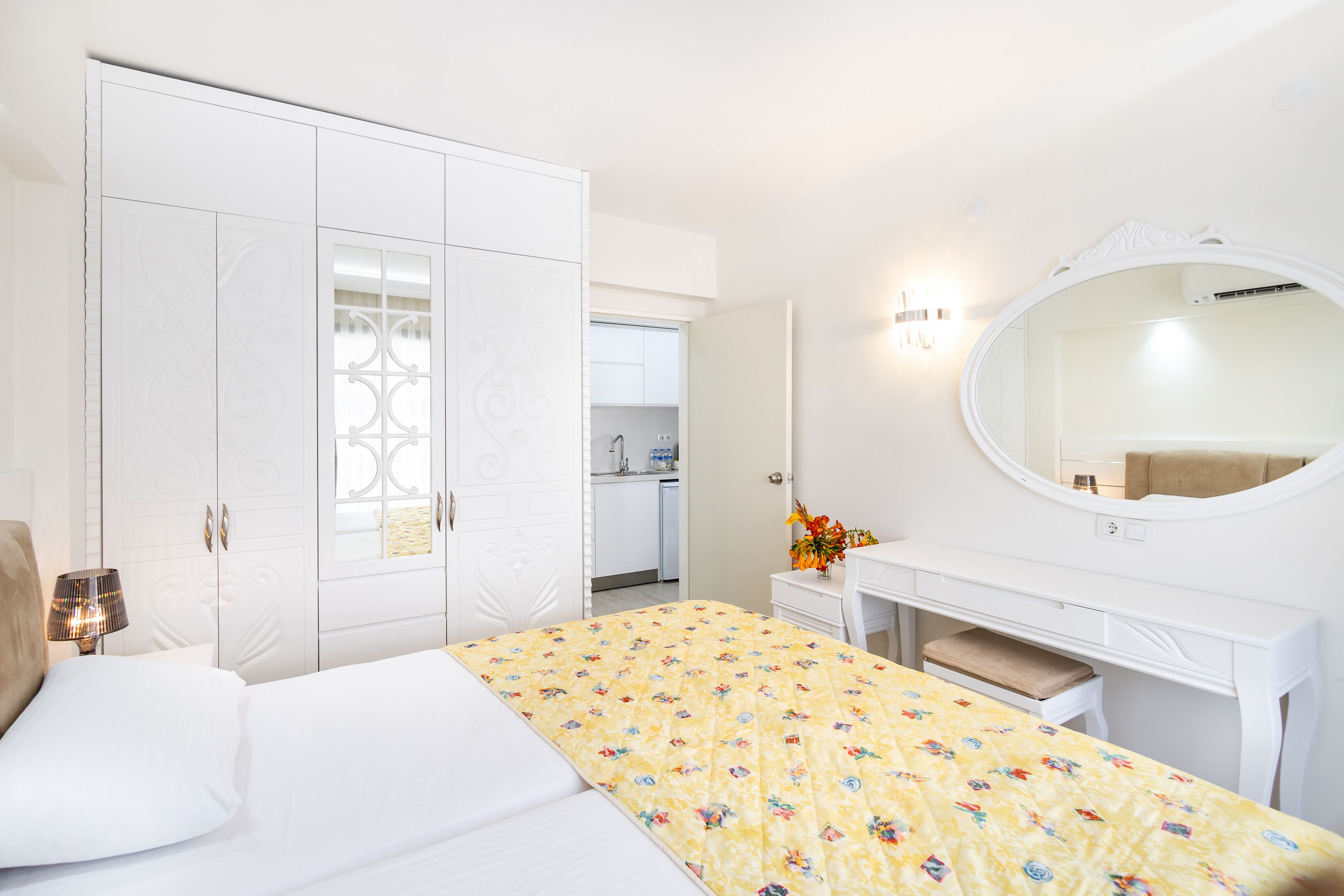 Habitació d'hotel amb un llit, una tocador amb mirall i un armari.
