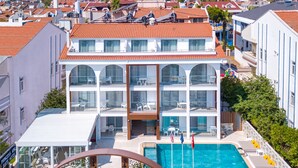 A multi-story hotel with a swimming pool, balconies, and a view of the surrounding town and mountains. - Princess Kinli Suites Hotel (Marmaris)