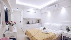 A modern hotel room with a neatly made bed, a small kitchenette, and a bathroom. - Princess Kinli Suites Hotel (Marmaris)