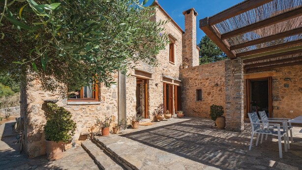 Un bâtiment en pierre doté d’un patio, d’un espace extérieur aménagé avec des sièges et de plantes en pot.