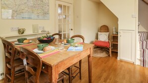 A dining area with a wooden table, chairs, a map on the wall, and a staircase leading to another room. - Bedford Terrace (Bridport)