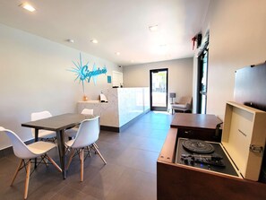 A reception area with a marble counter, a neon sign, a table with chairs, and a jukebox. - Signature Inn Santa Clara (Santa Clara)