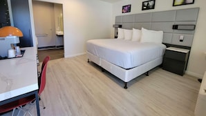 Ein modernes Hotelzimmer mit Bett, Nachttischen, einem Schreibtisch mit Lampe und einem Sessel.