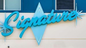 Ein Gebäude mit einem Schild, das in stilisierter Schrift 'Signature' zeigt.