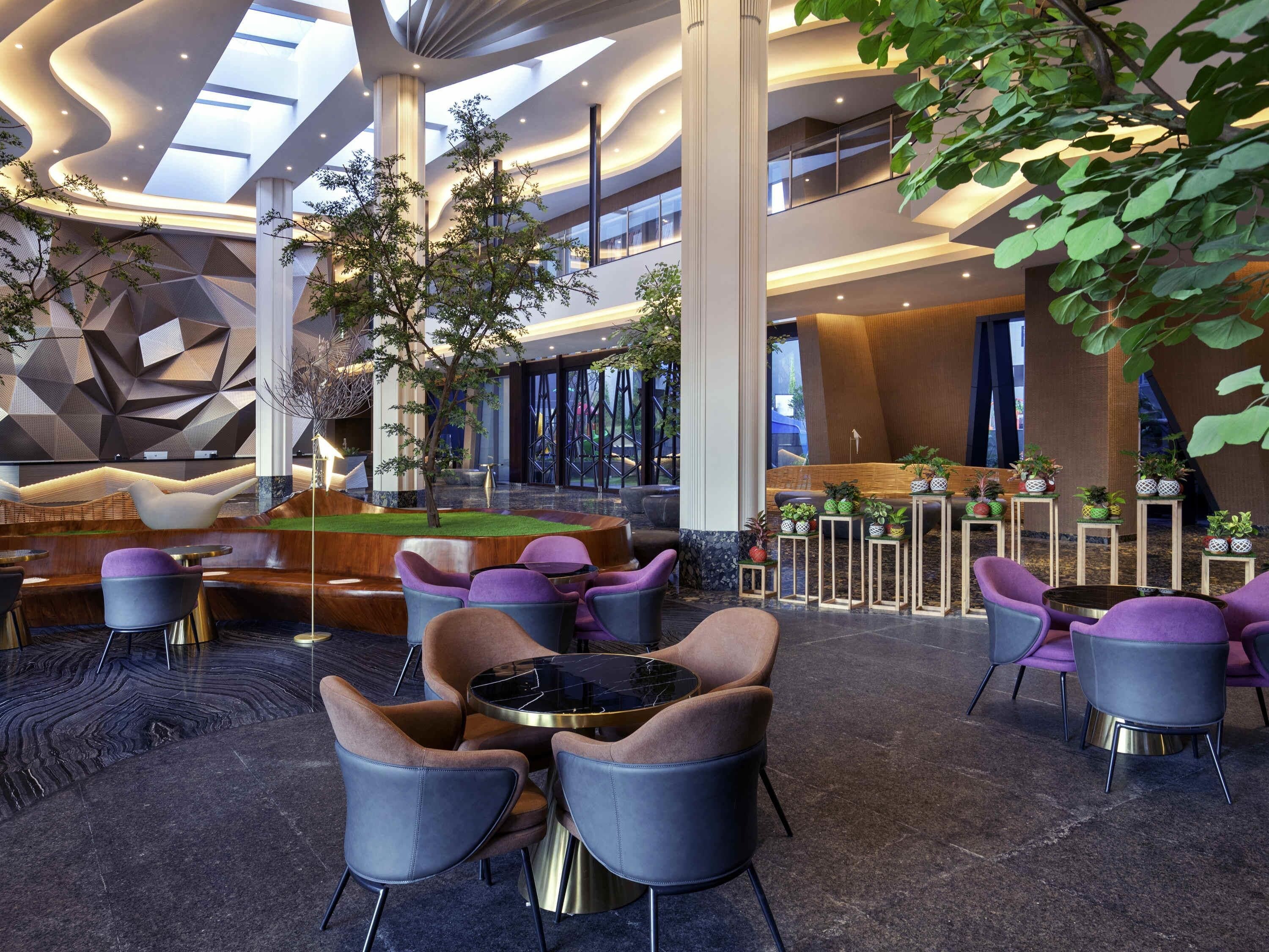 A modern lobby with a pool table, seating area, and indoor plants.