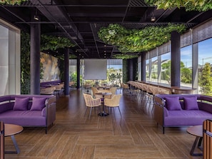 A spacious indoor area with high ceilings, large windows, and a variety of seating arrangements including sofas and chairs. - Grand Mercure Malang Mirama (Malang)