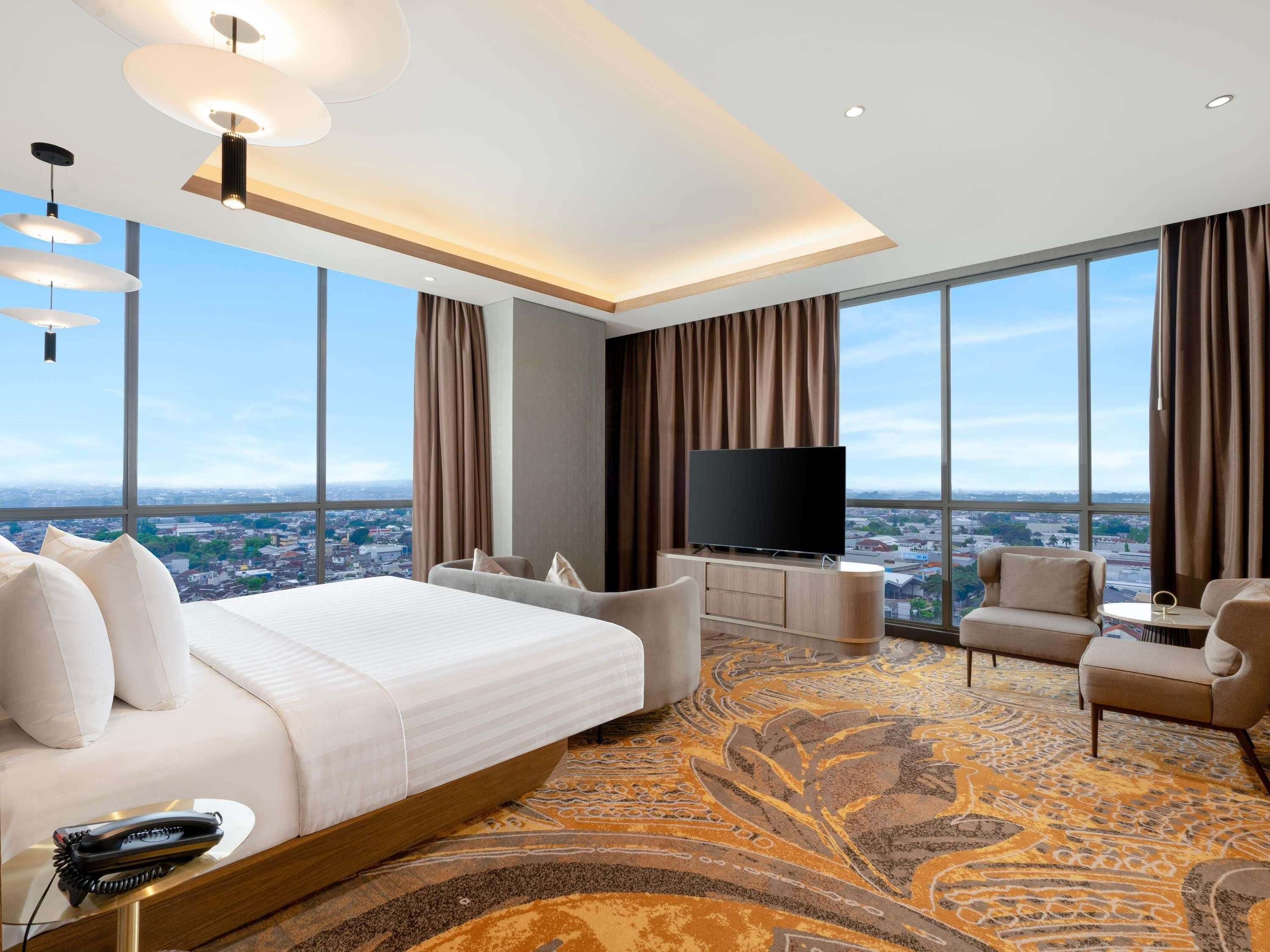 Habitación de hotel moderna con una cama grande, un televisor, un sofá y vistas a la ciudad.