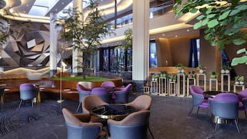 A modern lobby with a pool table, seating area, and indoor plants.