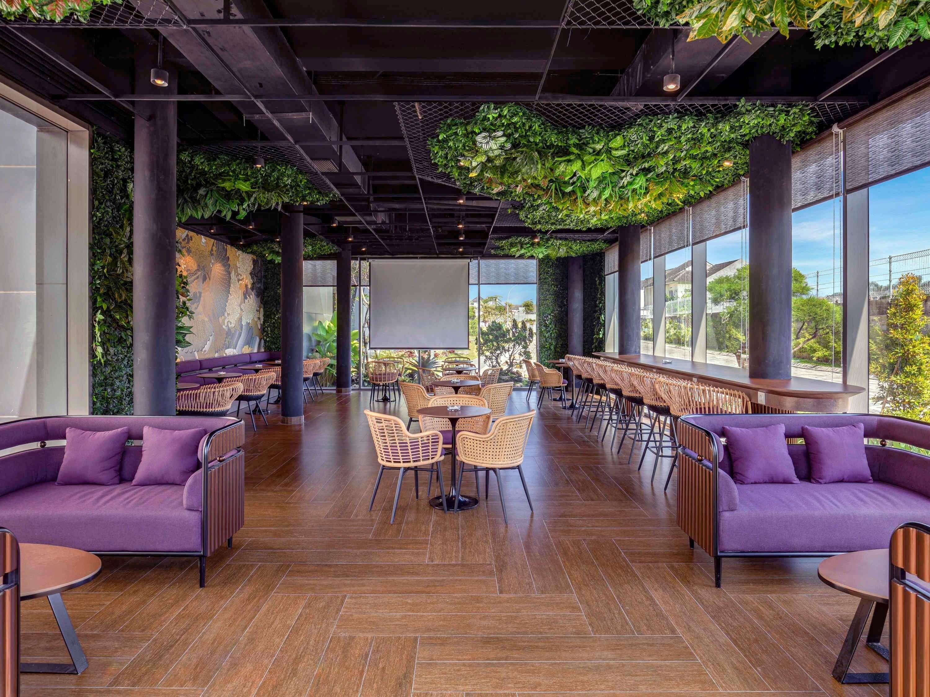 A spacious indoor area with high ceilings, large windows, and a mix of seating arrangements including sofas and tables.
