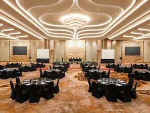 A conference room with round tables, black chairs, and a central stage.