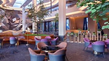 A modern interior with a central seating area, multiple levels, and a large tree.