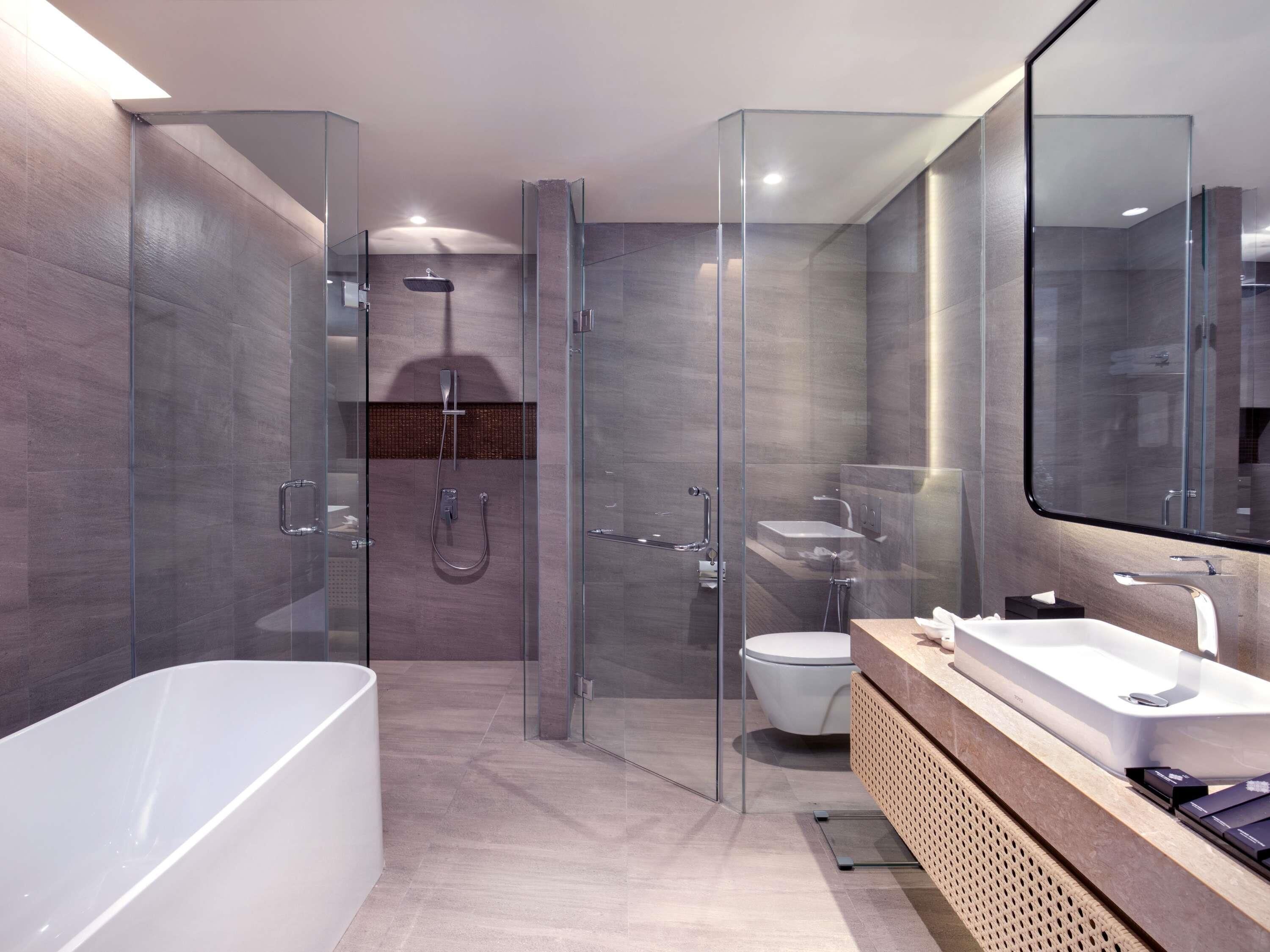 A modern bathroom with a glass-enclosed shower, a separate toilet, and a bathtub.