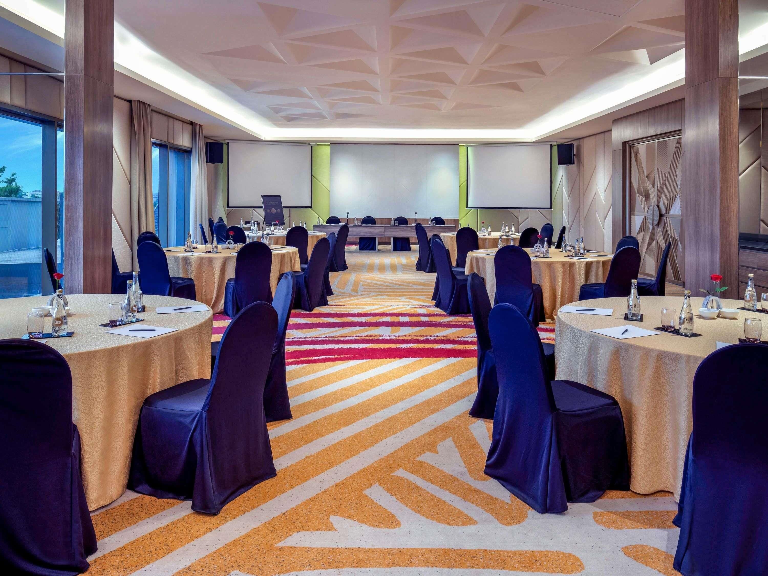 A conference room with round tables, chairs, and a presentation screen.