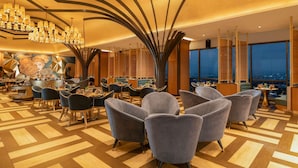 Un moderno vestíbulo de hotel con un área de estar central, un bar y un gran mural.