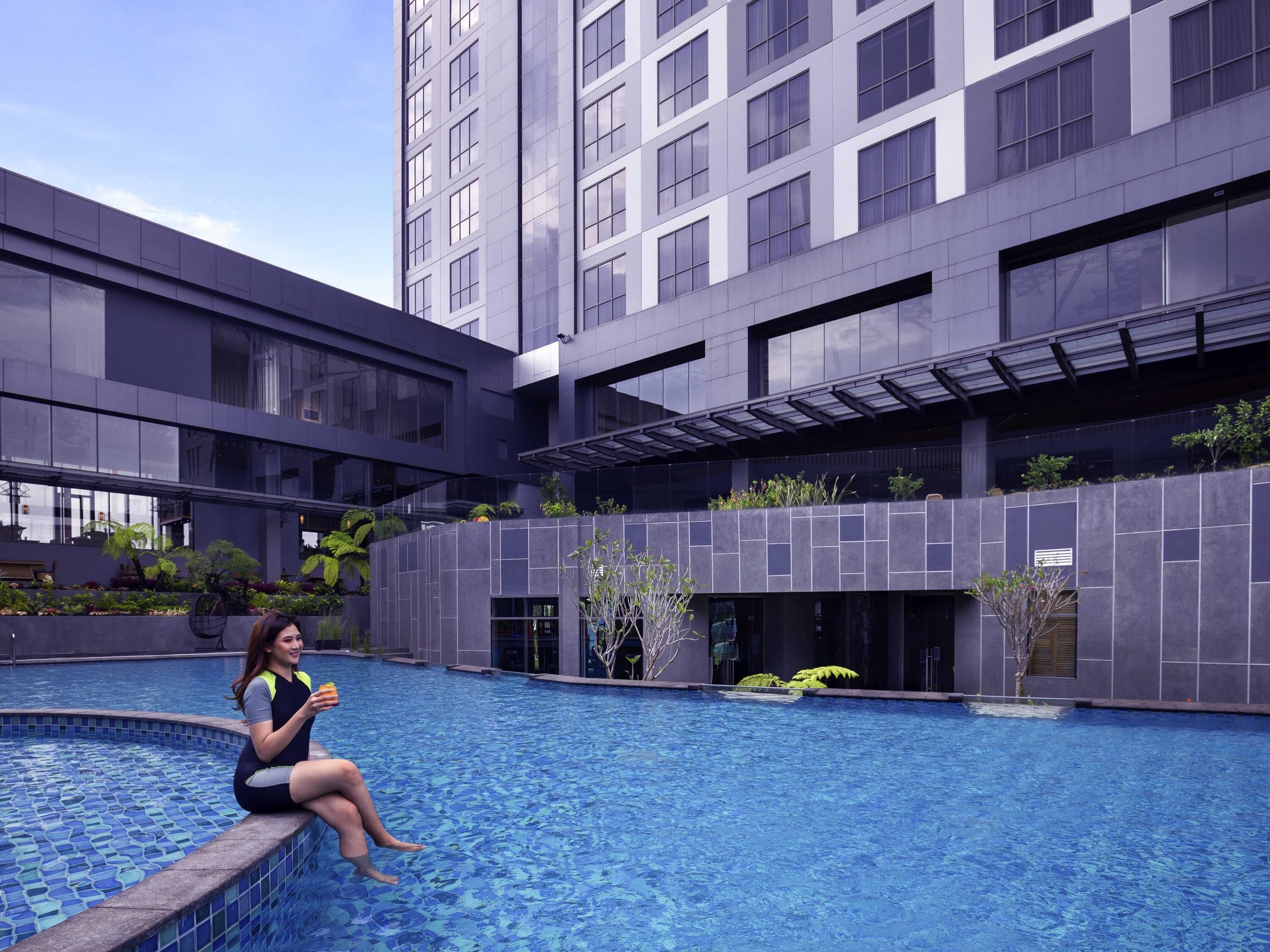 Un edificio moderno con piscina, ventanas amplias y un espacio al aire libre cubierto.