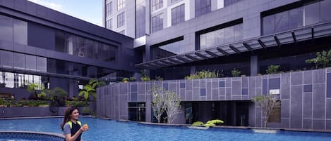 Un edificio moderno con piscina, ventanas amplias y un espacio al aire libre cubierto.