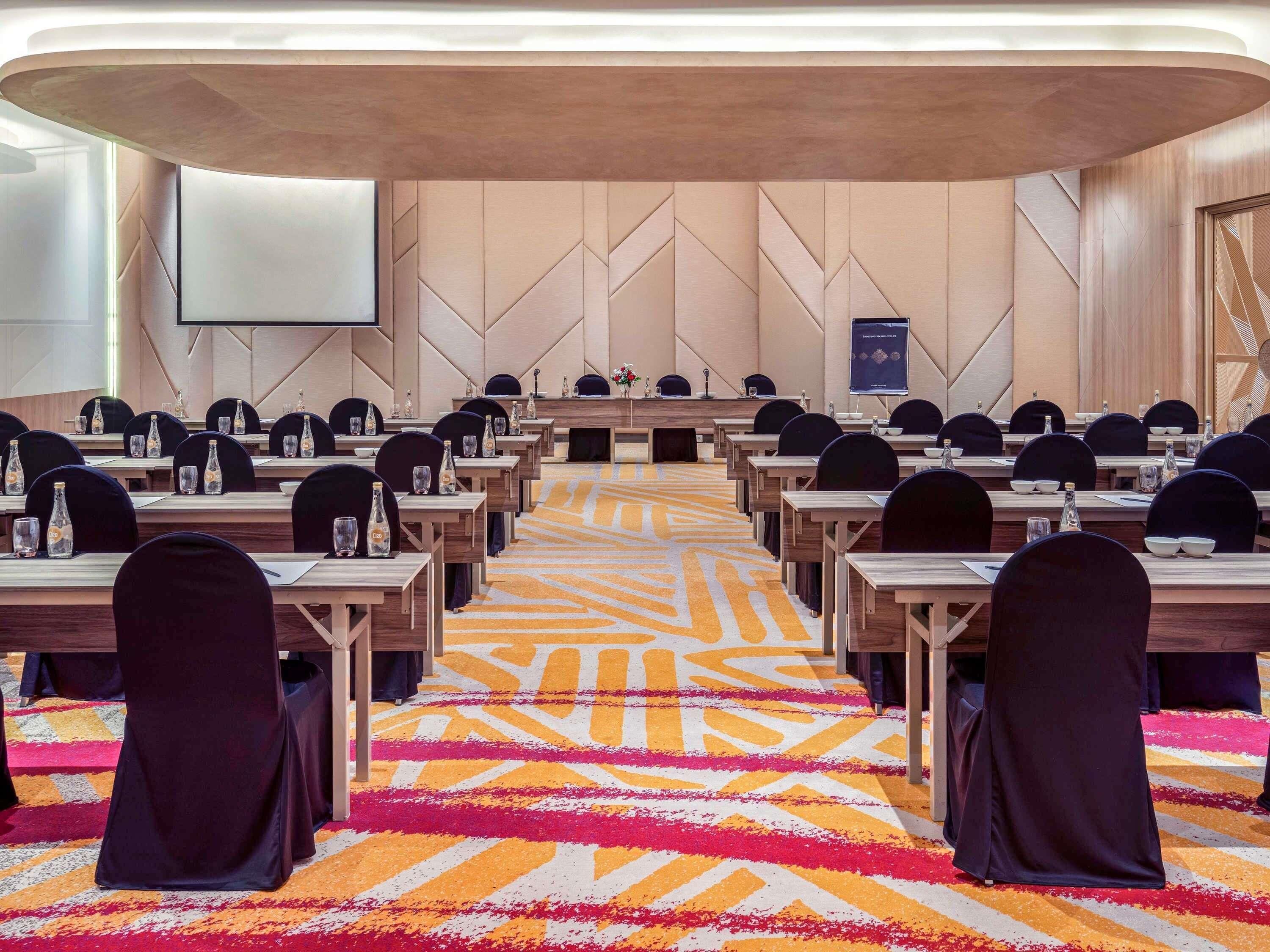 A conference room with a long table, chairs, and a carpeted floor.