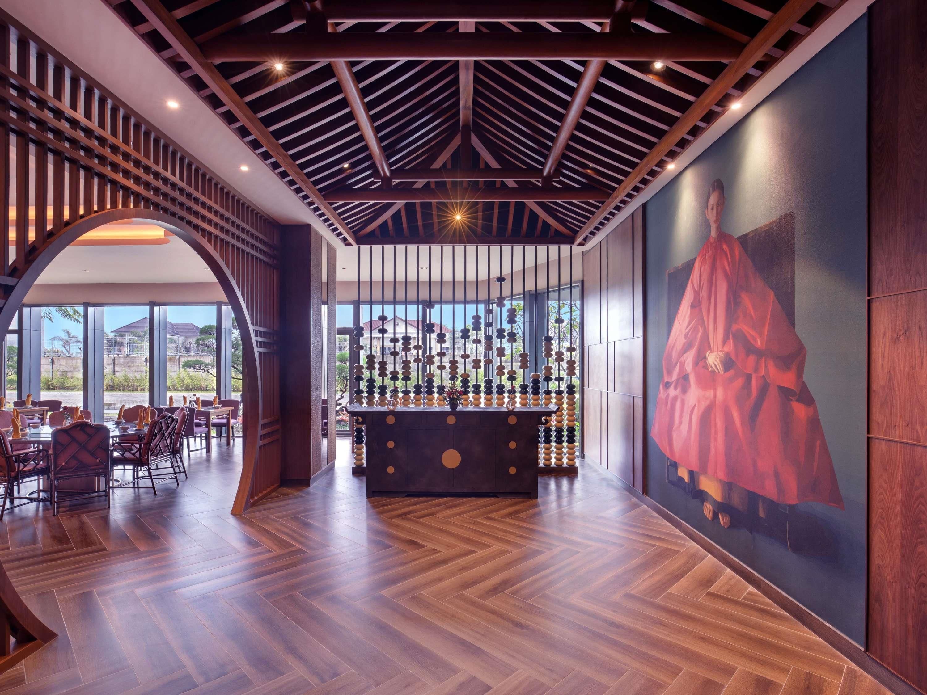 A modern bar area with a wooden ceiling, a large painting on the wall, and a view of the outdoors through large windows.