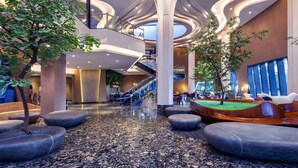 Un moderno vestíbulo con una escalera central, amplias columnas y plantas de interior.
