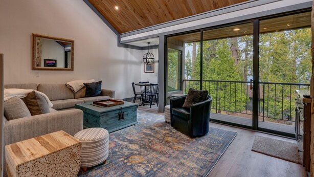 A modern living room with a wooden ceiling, large windows, a sofa, a coffee table, and a dining area. - Esperanzas Lakeside Retreat: 3  BR, 2  BA Condominium in Tahoma, Sleeps 6 (Tahoma)