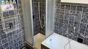 Ein Badezimmer mit Duschkabine, Badewanne und Fliesenwand.