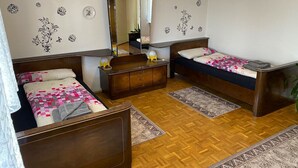 Ein Zimmer mit zwei hölzernen Betten, einem Holzschrank, einem Spiegel und einer Pendelleuchte.