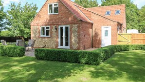 Une maison en briques avec une façade en pierre, une porte blanche et une petite fenêtre.