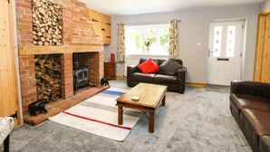 Un salon avec une cheminée en briques, un canapé avec des coussins, une table basse et un tapis.