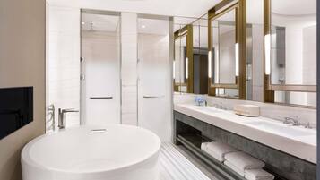 Een moderne badkamer met een vrijstaand bad, een wastafel met een grote spiegel en een douche.