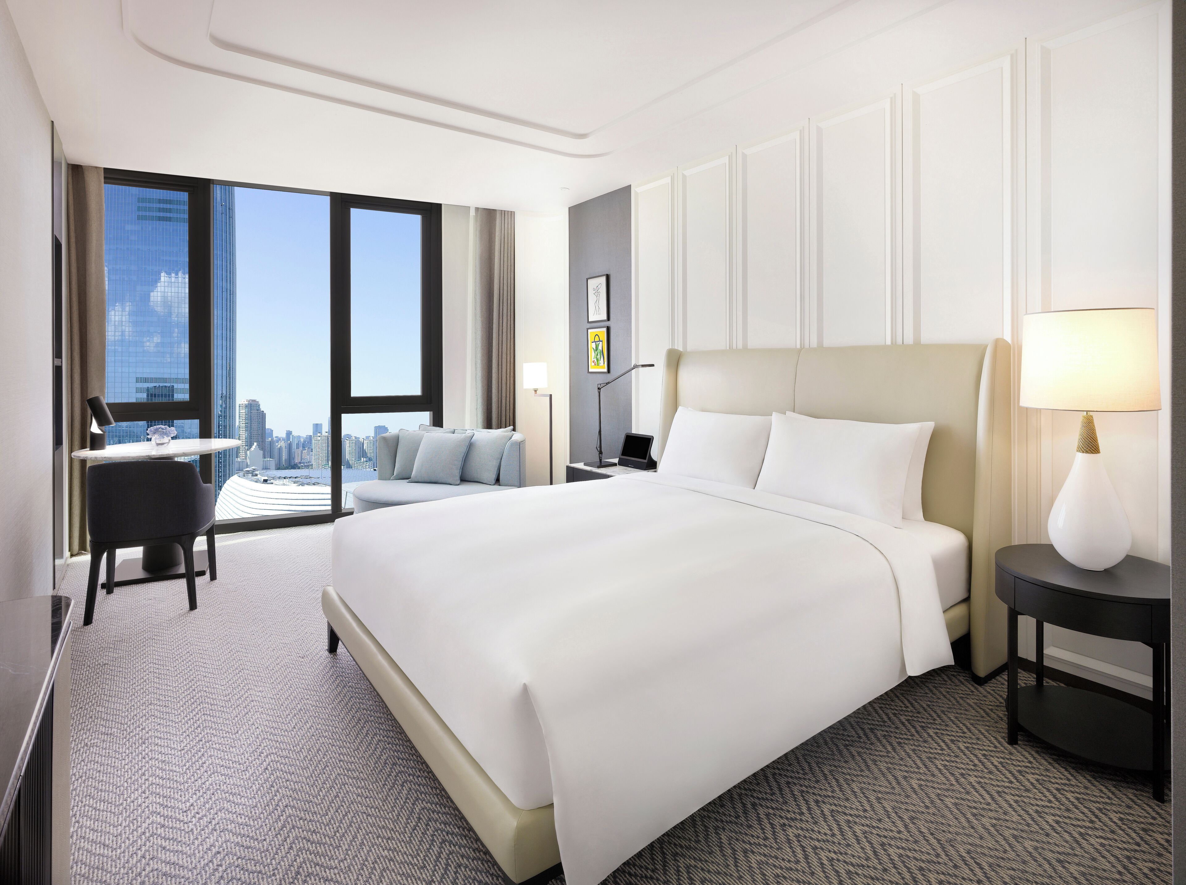 Una habitación de hotel moderna con una cama grande, un escritorio y vistas a la silueta urbana.